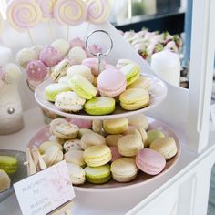 two tiered plates filled with macaroons and other desserts on top of a table