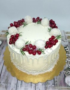 a white cake topped with cherries and flowers on top of a wooden table next to silverware