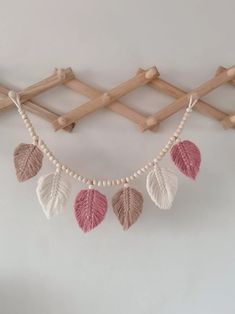 a string with leaves hanging from it next to a wooden wall mounted rack on the wall