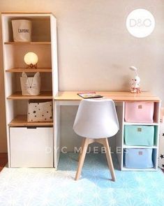 a white desk sitting next to a book shelf filled with books and toys on top of a blue rug