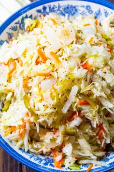 a blue and white bowl filled with coleslaw slaw salad on top of a wooden table