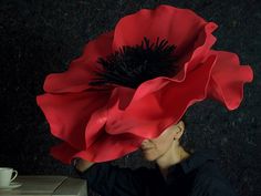 a woman with a large red flower on her head and a coffee cup in front of her