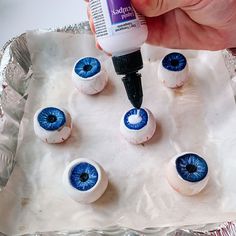 someone is painting fake blue eyeballs on a sheet of aluminum foil and glue to make them look like they have eyes