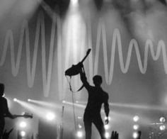 a man on stage with his arms in the air and lights behind him, holding a microphone