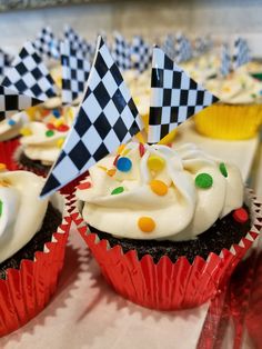 cupcakes decorated with white frosting and black and white checkerboard flags