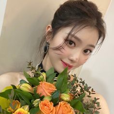 a woman holding a bouquet of flowers in front of her face and looking at the camera