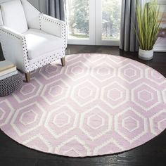 a living room with a white chair and pink rug on the floor in front of a window