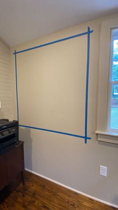 an empty room with blue tape on the wall and a black stove top oven in the corner