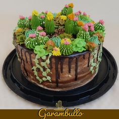 a cake decorated with flowers and cacti is on a black platter that says garambullo