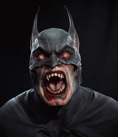 a man in a batman costume with red eyes and fangs on his face is looking at the camera