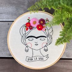 a cross stitch hoop with a woman's face and flowers in her hair