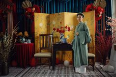 a woman standing next to a table with flowers on it