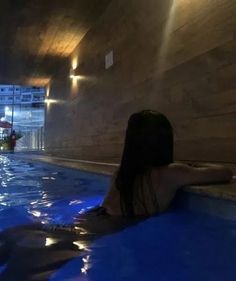 a woman sitting in the middle of a swimming pool with her back to the camera