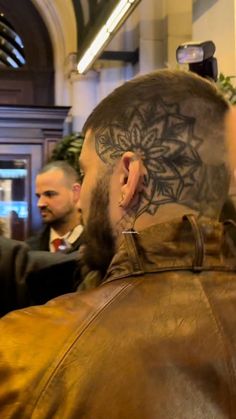 a man with a tattoo on his head standing next to another man in a suit