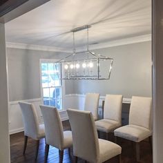 a dining room table with white chairs and a chandelier