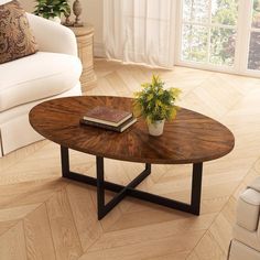 a coffee table with a book and plant on it in front of a white couch