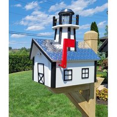 a house shaped like a lighthouse with a clock on it's roof and solar panels