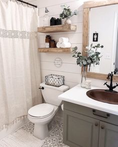 a white toilet sitting next to a bathroom sink under a mirror and a shower curtain