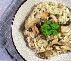 a white plate topped with rice covered in mushrooms and garnished with parsley