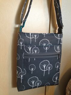 a black and white bag hanging on a door handle with trees printed on the front