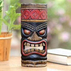 a tiki mask sitting on top of a table next to a potted plant