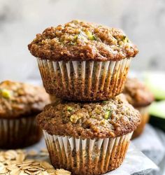 three zucchini muffins stacked on top of each other in front of sliced cucumbers