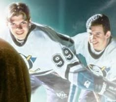 two hockey players standing next to each other in front of a large screen with an image of them on it