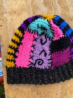 a multicolored knitted hat sitting on top of a wooden table