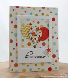 a happy birthday card with balloons and stars on the front, sitting on top of a wooden table