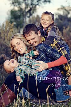 a man and two children are sitting on the ground with their arms around each other