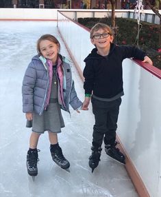 two children standing on an ice rink holding hands