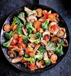 a skillet filled with broccoli, mushrooms and tomatoes