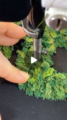 someone is using a drill to make a wreath out of fake moss and other things