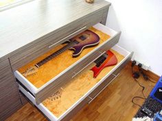 two guitars are sitting in a drawer on the floor