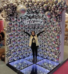 a woman standing in front of a display with silver balls on it's sides