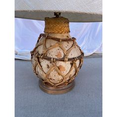 an old vase with wicker on it is sitting under a table cloth covered umbrella