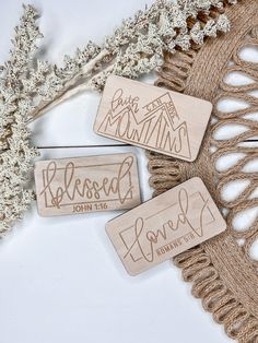 three wooden name tags sitting on top of a piece of string next to some white flowers