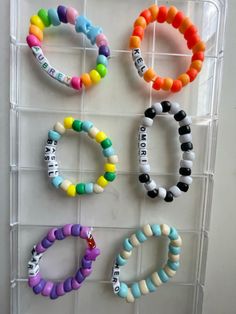 four different bracelets are hanging on a rack with plastic beads and magnets attached to them