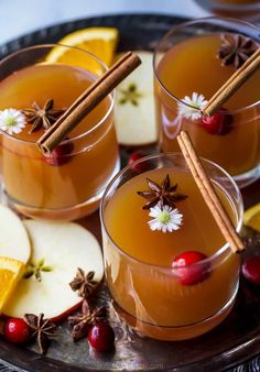 two glasses filled with apple cider and cinnamon sticks