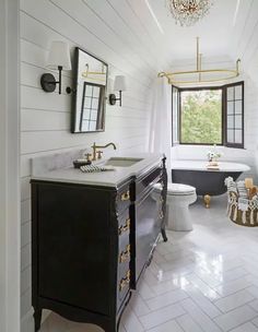 a white bathroom with black and gold fixtures on the vanity, sink, toilet and tub