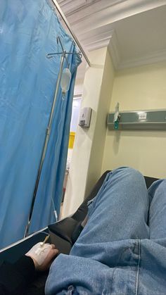 a person laying in a hospital bed next to a blue curtain