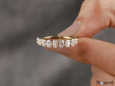 a woman's hand holding a gold ring with five diamonds on it and the middle finger