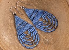 a pair of blue beaded earrings sitting on top of a tree stump