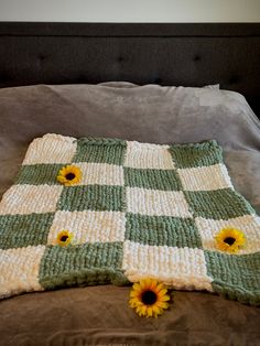 a crocheted blanket with sunflowers sitting on top of it in the middle of a bed