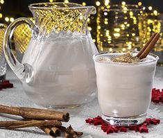 two mugs of hot chocolate and cinnamon on a table with lights in the background