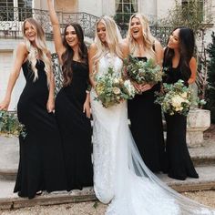 a group of women standing next to each other in front of a building with flowers