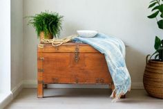 a wooden trunk with a blanket and potted plant on top