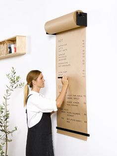 a woman standing in front of a wall with a large poster hanging on it's side