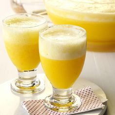 two glasses filled with orange juice on top of a table