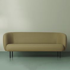 a tan couch sitting on top of a green floor next to a white wall in an empty room